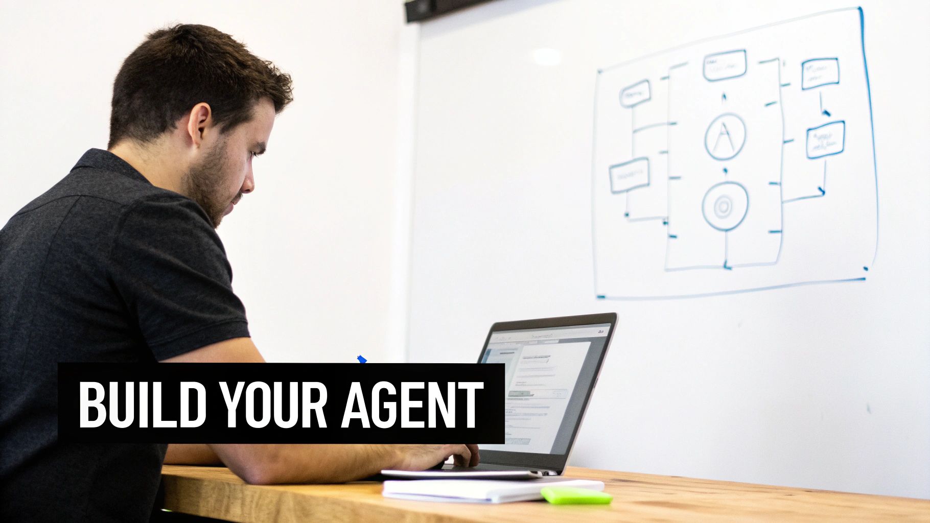 A focused man develops an agent on his laptop, with a technical flowchart drawn on a whiteboard.