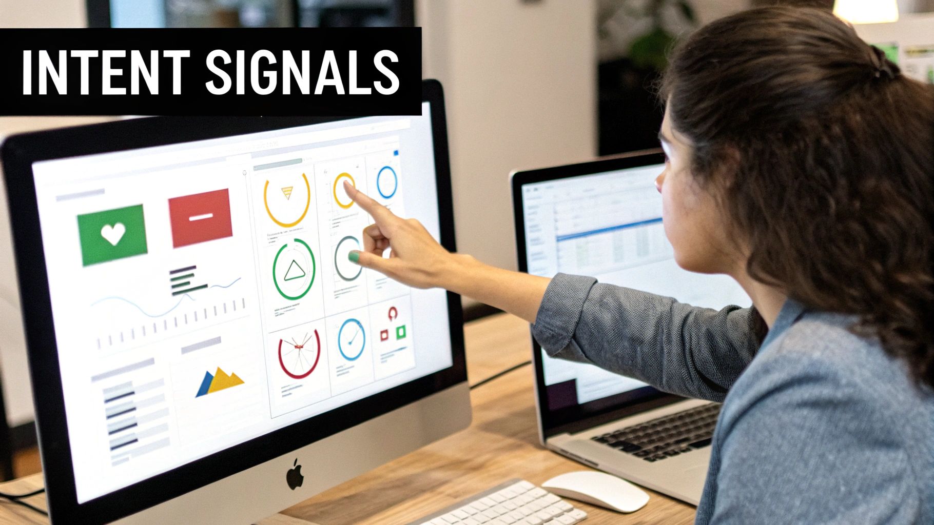 Woman analyzing 'Intent Signals' data on a desktop computer, pointing at charts and graphs.