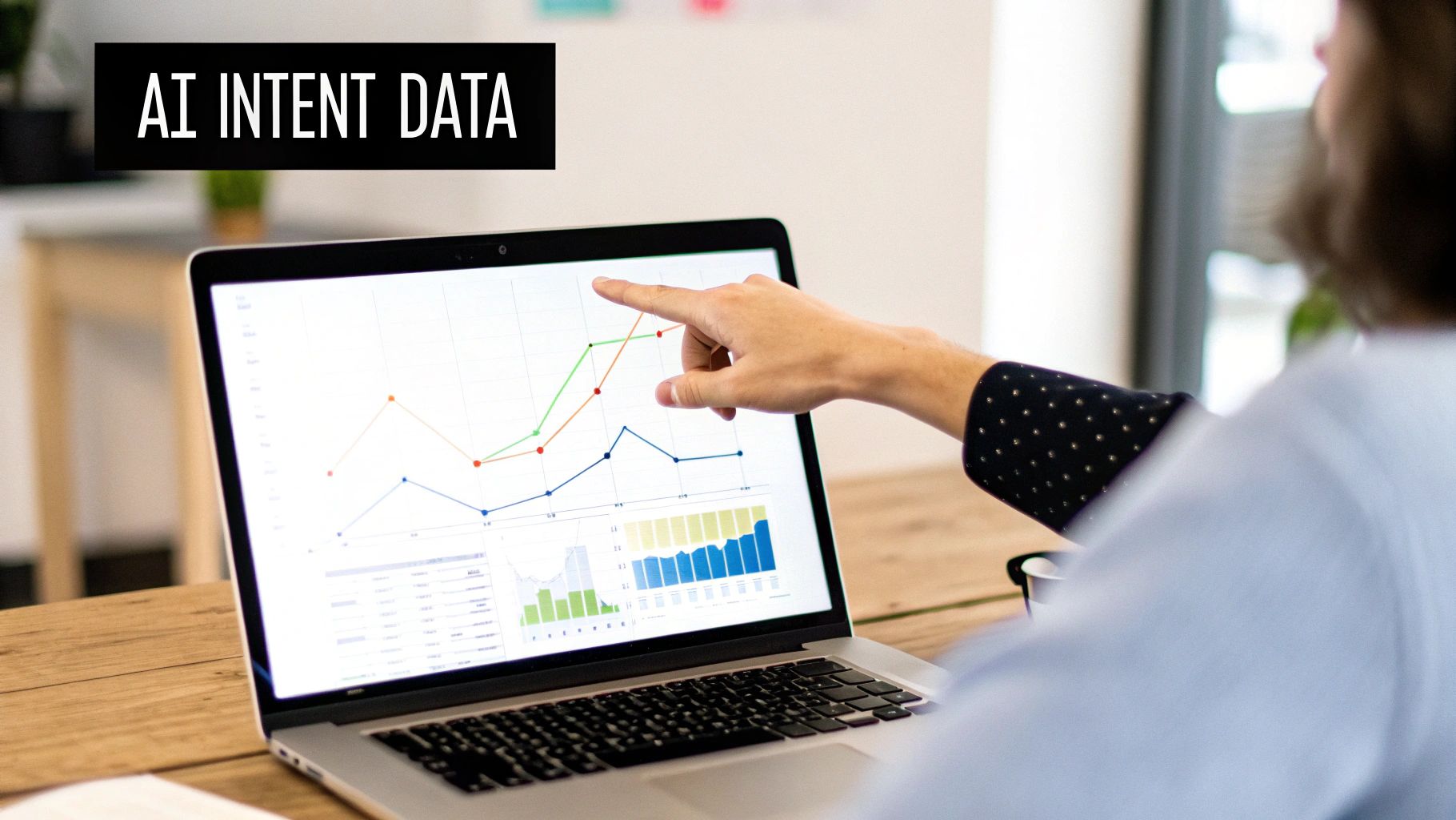 A person points at a laptop screen displaying AI intent data charts and graphs.