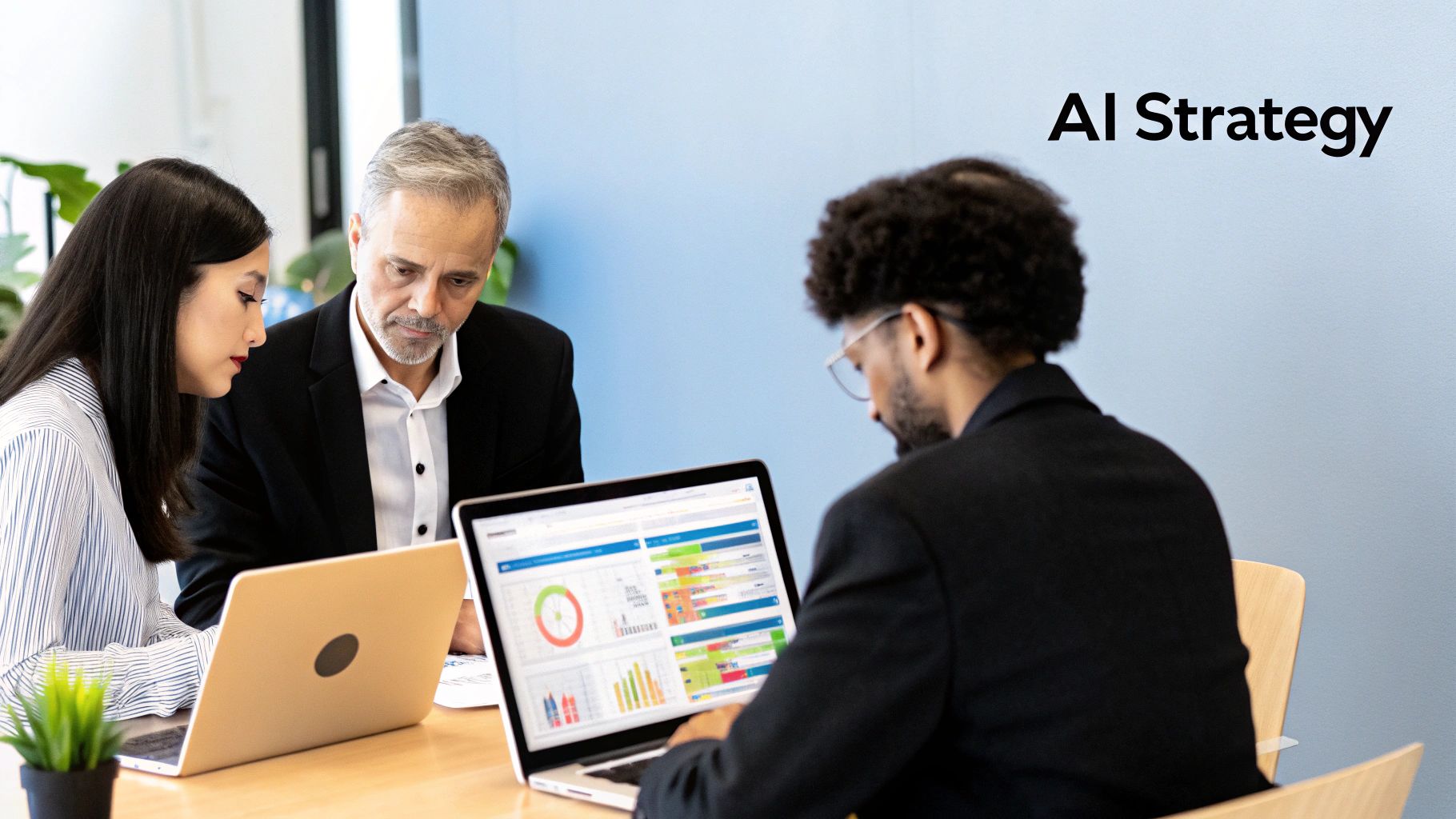 Three business professionals review data on laptops during an AI strategy meeting.