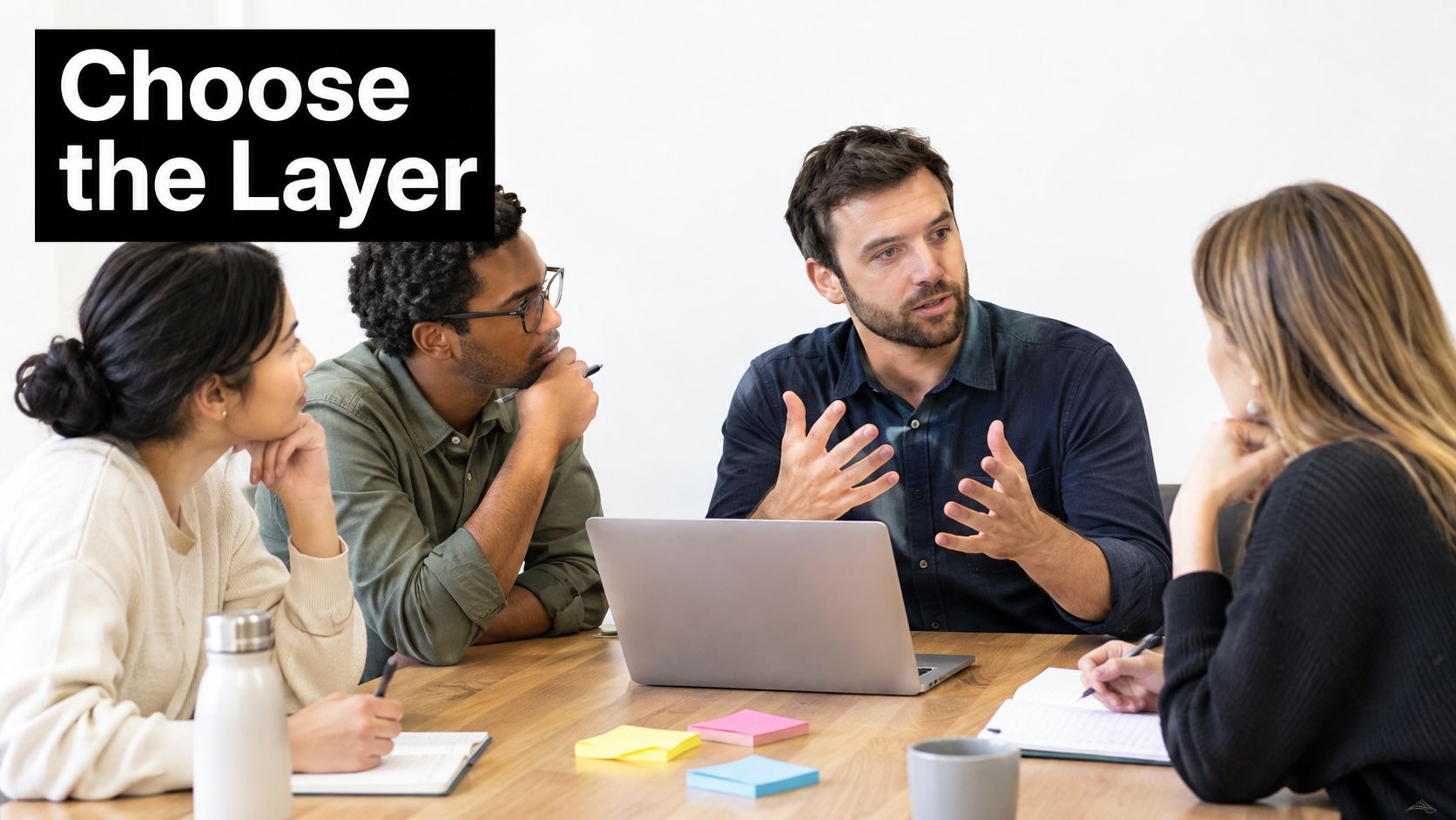 A diverse group of professionals collaborating in a meeting at a table with a laptop.